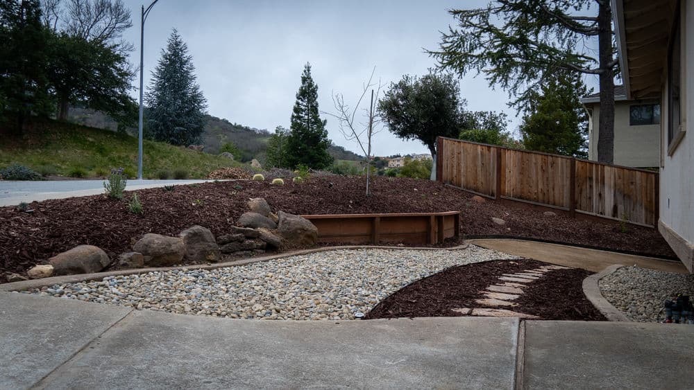 Landscaped front yard with gravel, mulch, and plants along a curved pathway.