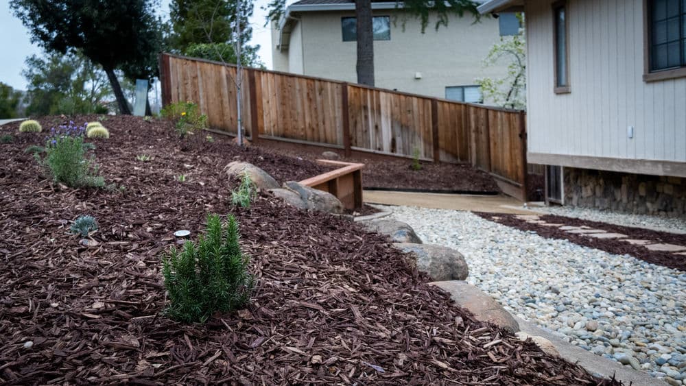 Landscaped yard with mulch, rocks, and a wooden fence creating an inviting outdoor space.